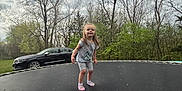 Anna joined the competition — help win amazing prizes! activity, backyard, car, casual_clothing, child, cloudy_sky, daytime, footwear, girl, grass, happy, leisure, nature, outdoor, person, playing, smiling, spring, trampoline, tree