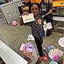 Nyla joined the competition — help win amazing prizes! child, girl, smiling, jewelry, gift, party, indoor, bench, bags, colorful, floor, people, casual, hair, tattoos, orange_socks, balloon, table, present, celebration