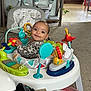 Nova is registered to the contest to win money with this photo: baby, child, smiling, indoor, activity_center, toys, colorful, face, happy, person, carpet, furniture, seat, play, giraffe_toy, elephant_toy, flower_toy, green_toy, wood_table, remote_control