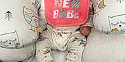 Nova is registered to the contest to win money with this photo: baby, infant, smiling, bib, pink, owl_pattern, cushion, blanket, socks, onesie, happy, child, cute, indoor, seated, portrait, soft_toys, comfort, cozy, young