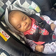 Nova is registered to the contest to win money with this photo: baby, sleeping, car_seat, safety_harness, pink_clothing, hood, infant, child, seat_belt, cozy, peaceful, toddler, resting, cute, indoor, soft, patterned, young_child, transport, car_interior