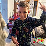 child, pajamas, indoor, living_room, toys, furniture, smile, person, candid, playful, cozy, carpet, couch, blurred_background, colorful_clothing, happy, young_boy, portrait, home, fun