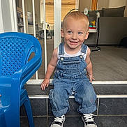 Riley joined the competition — help win amazing prizes! toddler, child, denim_overalls, sneakers, blue_chair, smiling, indoor, living_room, carpet, tile_floor, baby_gate, furniture, play_area, door, window, curtains, person, cute, happy, portrait
