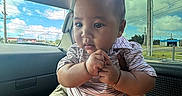 Eziah joined the competition — help win amazing prizes! baby, child, car_interior, window, sky, clouds, power_lines, shorts, striped_shirt, hand, face, expression, curious, seat, person, indoor, daylight, casual_clothing, skin, head