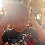 Alexander is registered to the contest to win money with this photo: backlighting, batman, blonde_hair, blue_eyes, child, close_up, clothing, comic_book, curly_hair, golden_hour, hands, home, indoors, playful, portrait, smiling, sunlight, superhero_shirt, superman, warm_lighting
