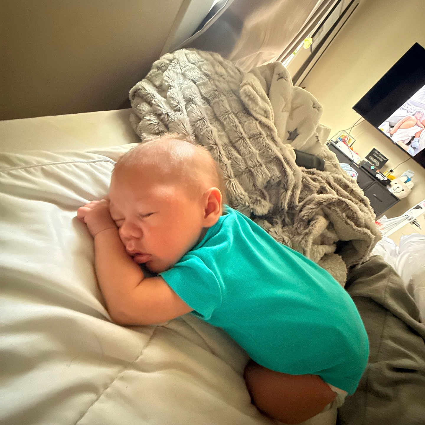 Neteyam is registered to the contest to win money with this photo: baby, sleeping, bed, blanket, onesie, infant, peaceful, indoor, cozy, furniture, television, curtains, soft_lighting, home, resting, child, person, white_bedspread, blanket_texture, relaxation