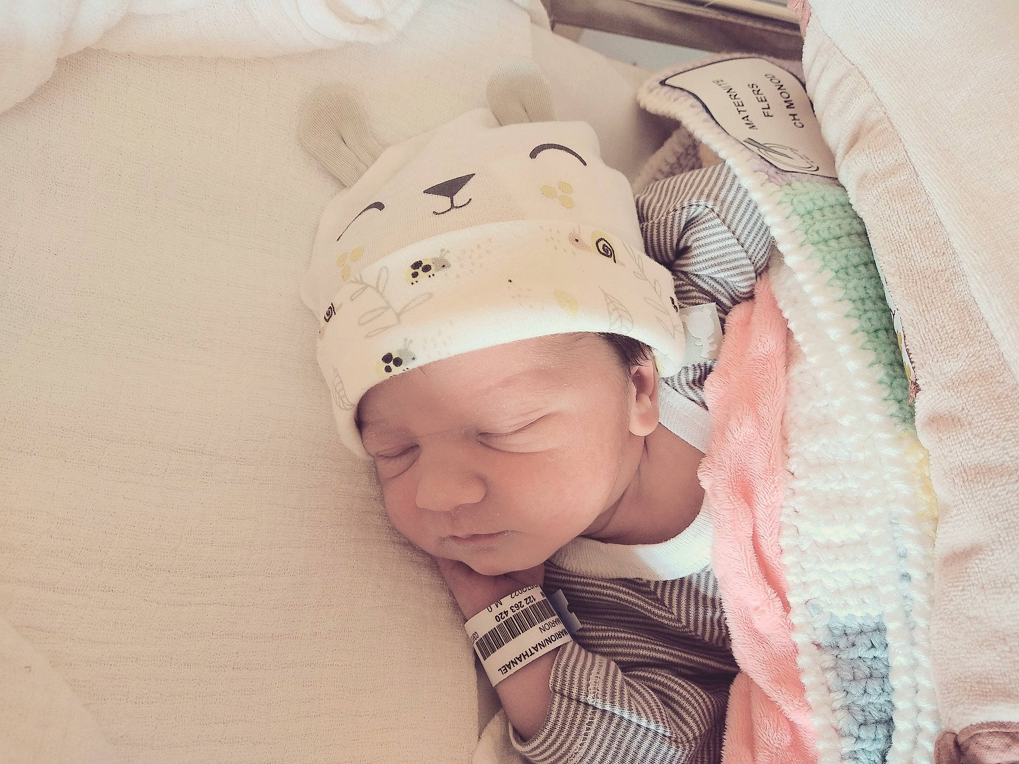 Nathanaël a rejoint le concours — aidez-le/la à gagner de superbes lots ! baby, baby_products, baby_safety, baby_sleeping, baby_toddler_clothing, beanie, bedding, bonnet, cap, child, comfort, fashion_accessory, hair_accessory, knit_cap, linens, pattern, peach, person, room, sleeve