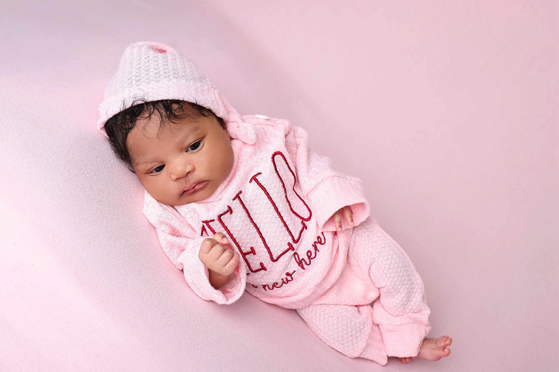 Aliana joined the competition — help win amazing prizes! baby, infant, pink_clothing, knit_hat, knit_sweater, knit_pants, soft_texture, pastel_background, newborn, resting, portrait, cute, child, lying_down, indoors, warm, cozy, peaceful, face, hand