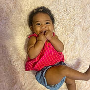 Harper is registered to the contest to win money with this photo: baby, child, smiling, happy, cute, infant, lying_down, pink_clothing, denim_shorts, fingers_in_mouth, curly_hair, headband, fluffy_rug, indoors, skin, face, person, one_child, casual_clothing, bright_colors