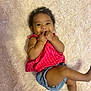baby, child, smiling, happy, cute, infant, lying_down, pink_clothing, denim_shorts, fingers_in_mouth, curly_hair, headband, fluffy_rug, indoors, skin, face, person, one_child, casual_clothing, bright_colors