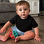 toddler, child, baby, indoor, floor, toy, ball, black_shirt, blue_shorts, barefoot, living_room, couch, kitchen, cabinet, wooden_floor, curious, sitting, person, home, cute
