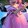 toddler, child, princess_dress, pink_dress, sparkly_shoes, toy_car, outdoor, grass, pond, happy, smiling, clapping, celebration, park, sunlight, cute, headband, ribbon, small_car, joyful