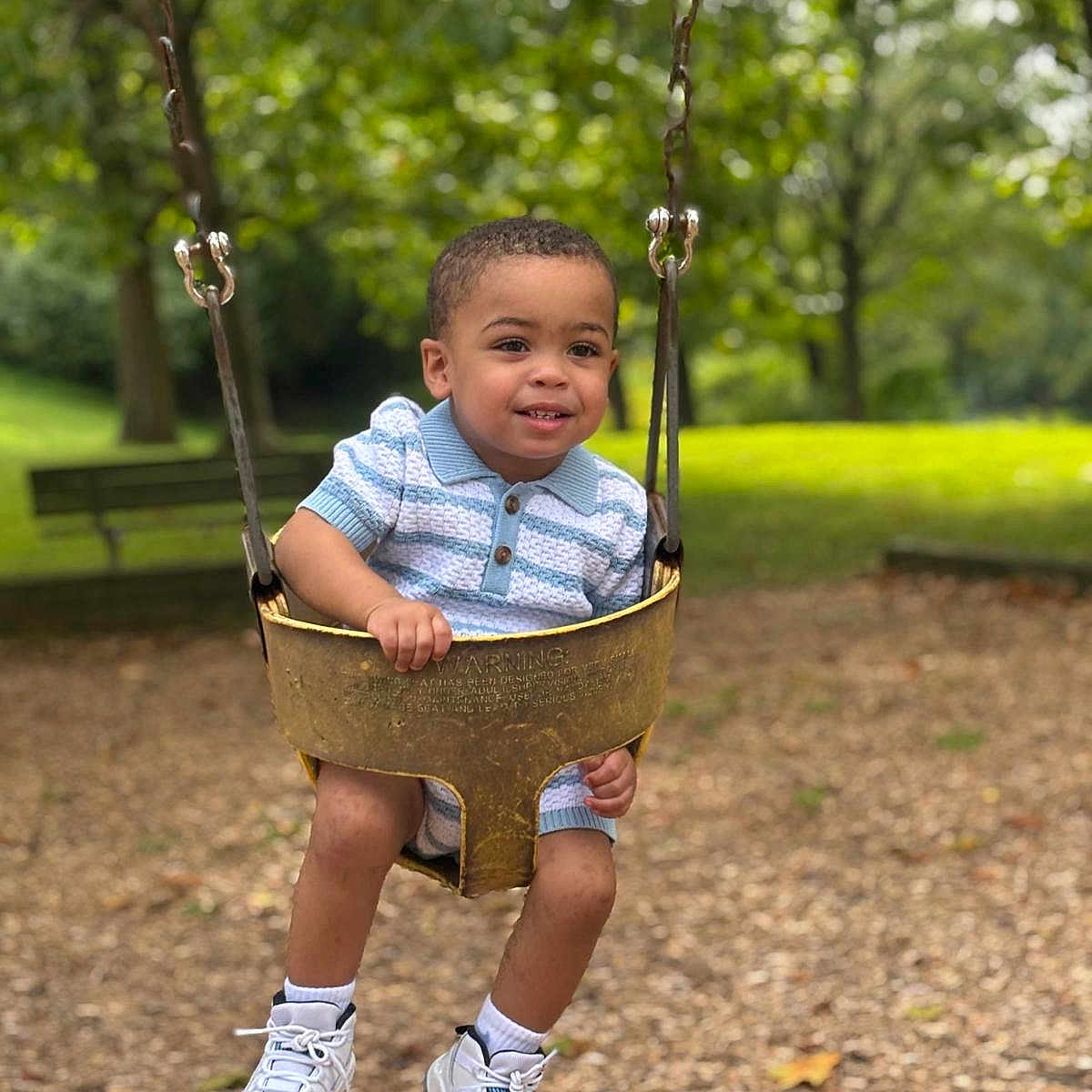 Tyler Ramirez joined the competition — help win amazing prizes! bench, child, clothing, cute, fun, grass, happy, outdoor, park, person, playground, recreation, shoes, smiling, summer, swing, toddler, trees, woodchips, young