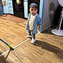 toddler, child, denim_shirt, jeans, cap, old_navy, kitchen, floor, fan, mop, wood_floor, appliances, person, indoor, clothing, footwear, expression, young_child, home, casual
