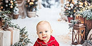 Tommy is registered to the contest to win money with this photo: baby, child, red_pajamas, smiling, sitting, white_rug, christmas_trees, lanterns, holiday, winter, snow, decorations, presents, festive, indoors, cute, portrait, happy, bright, seasonal