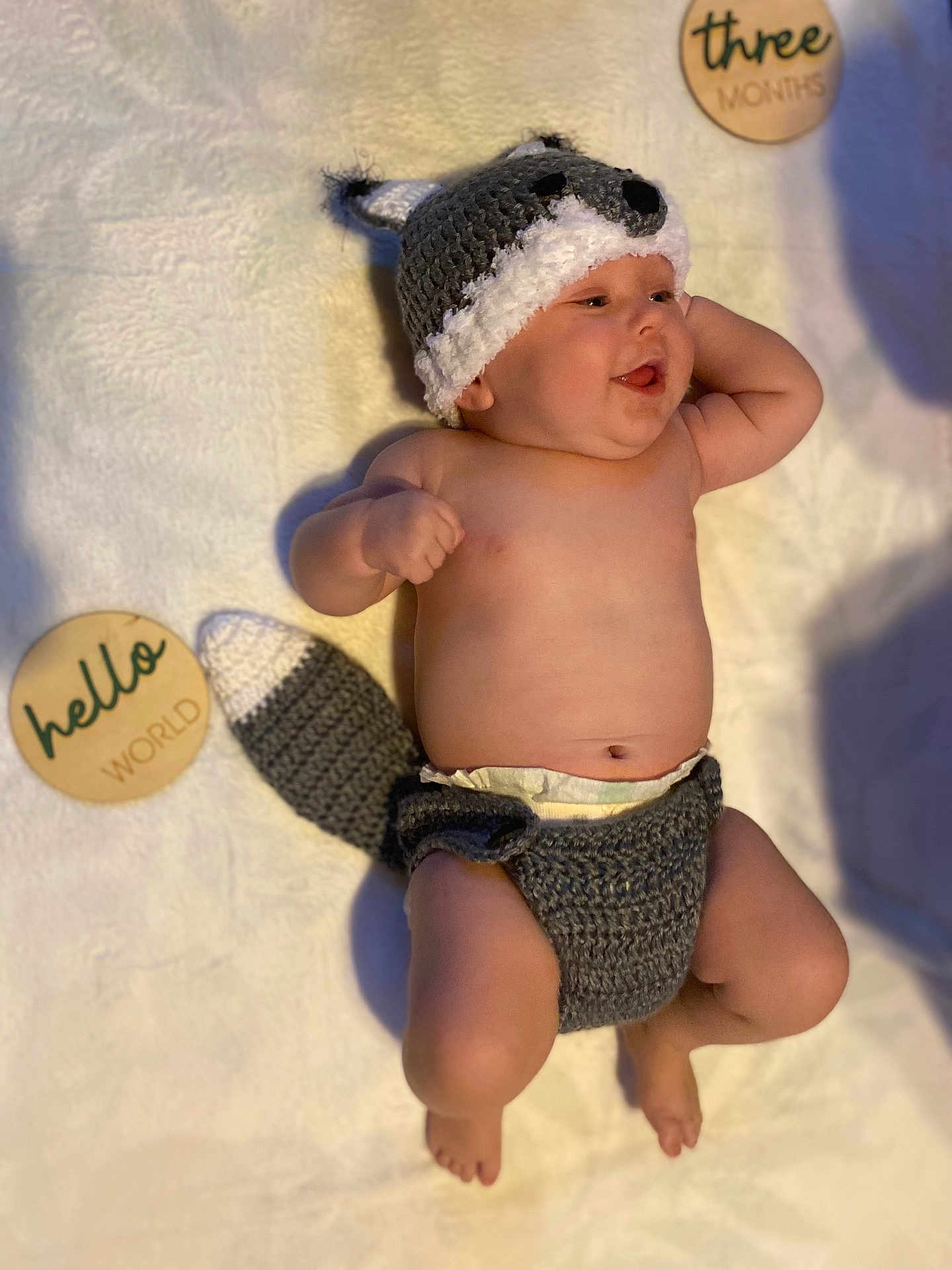 Julius joined the competition — help win amazing prizes! baby, infant, hat, knitted, diaper, blanket, milestone, wooden_sign, smiling, cute, chubby, lying_down, indoors, soft_texture, happy, face, person, child, headwear, newborn