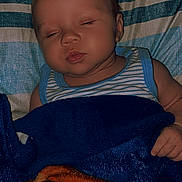 Julius is registered to the contest to win money with this photo: baby, sleeping, blanket, striped_sheet, cozy, infant, child, peaceful, face, hand, bed, blue, orange, white, striped, resting, cute, soft, portrait, indoors