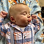 baby, blanket, cheeks, child, closeup, clothing, cute, expression, face, hands_up, indoors, infant, person, plaid_shirt, portrait, resting, sleeping, soft_light, suspenders, young_child