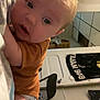 adult, arm, baby, bob_marley, brown_clothing, chair, child, curious, diaper, door, face, glasses, head, indoor, infant, person, room, skin, tattoo, towel