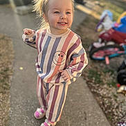 Korah joined the competition — help win amazing prizes! toddler, child, smiling, outdoor, sidewalk, sunlight, lens_flare, striped_clothing, topknot, toy, tricycle, happy, playful, casual_wear, footwear, person, daylight, young_child, hair_tie, background_blur