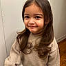 Aura joined the competition — help win amazing prizes! brown_hair, casual_clothing, child, cozy, curly_hair, cute, face, happy, indoor, light_skin, long_hair, person, portrait, room, smile, standing, sweater, wall, wooden_floor, young