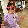 Arya joined the competition — help win amazing prizes! accessory, bracelet, casual, child, cute, fashion, furniture, heart_shaped, home, indoor, minnie_mouse, person, playful, purple_clothing, smiling, sunglasses, table, toddler, wooden_floor, young_child