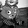 baby, black_and_white, child, clothing, cute, expression, eyes, face, floor, hand, happy, hoodie, indoor, infant, person, portrait, sitting, smiling, striped_socks, wooden_floor