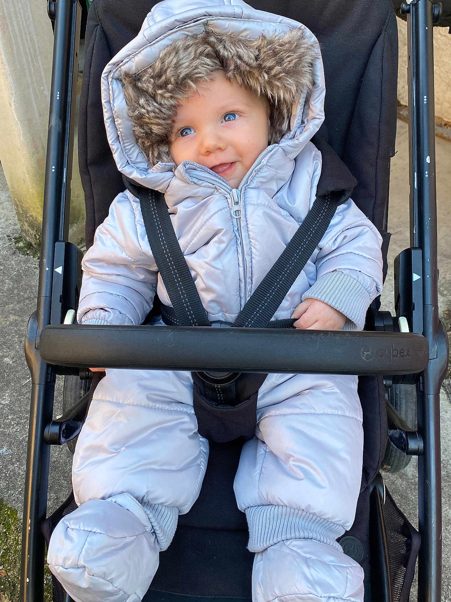 Avön a rejoint le concours — aidez-le/la à gagner de superbes lots ! baby, stroller, winter_clothing, snowsuit, hood, fur_trim, blue_eyes, smile, infant, child, outdoor, seatbelt, black_stroller, cute, cold_weather, jacket, mittens, happy, person, portrait