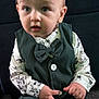 Reuben is registered to the contest to win money with this photo: toddler, child, boy, vest, bow_tie, shirt, green_clothing, sitting, carpet, indoor, curious_expression, hands, button, blond_hair, portrait, face, eyes, cute, young_child, fashion