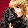 Angie a rejoint le concours — aidez-le/la à gagner de superbes lots ! woman, person, dog, black_dog, long_hair, blonde_hair, blue_eyes, face, portrait, close_up, cuddling, pet, companion, fluffy, long_ears, leather_jacket, red_background, studio, photography, collar