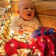 Kayne joined the competition — help win amazing prizes! baby, blanket, celebration, child, christmas_lights, cozy, cute, decorations, festive, gift_bag, happy, holiday, holiday_season, indoors, red_pants, sitting, smiling, toddler, warm, white_shirt