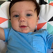 Jaylen joined the competition — help win amazing prizes! baby, infant, child, face, portrait, blue_shirt, brown_hair, blue_eyes, lying_down, blanket, geometric_pattern, bed, indoors, close_up, looking_at_camera, calm, drool, short_sleeves, colorful, photography