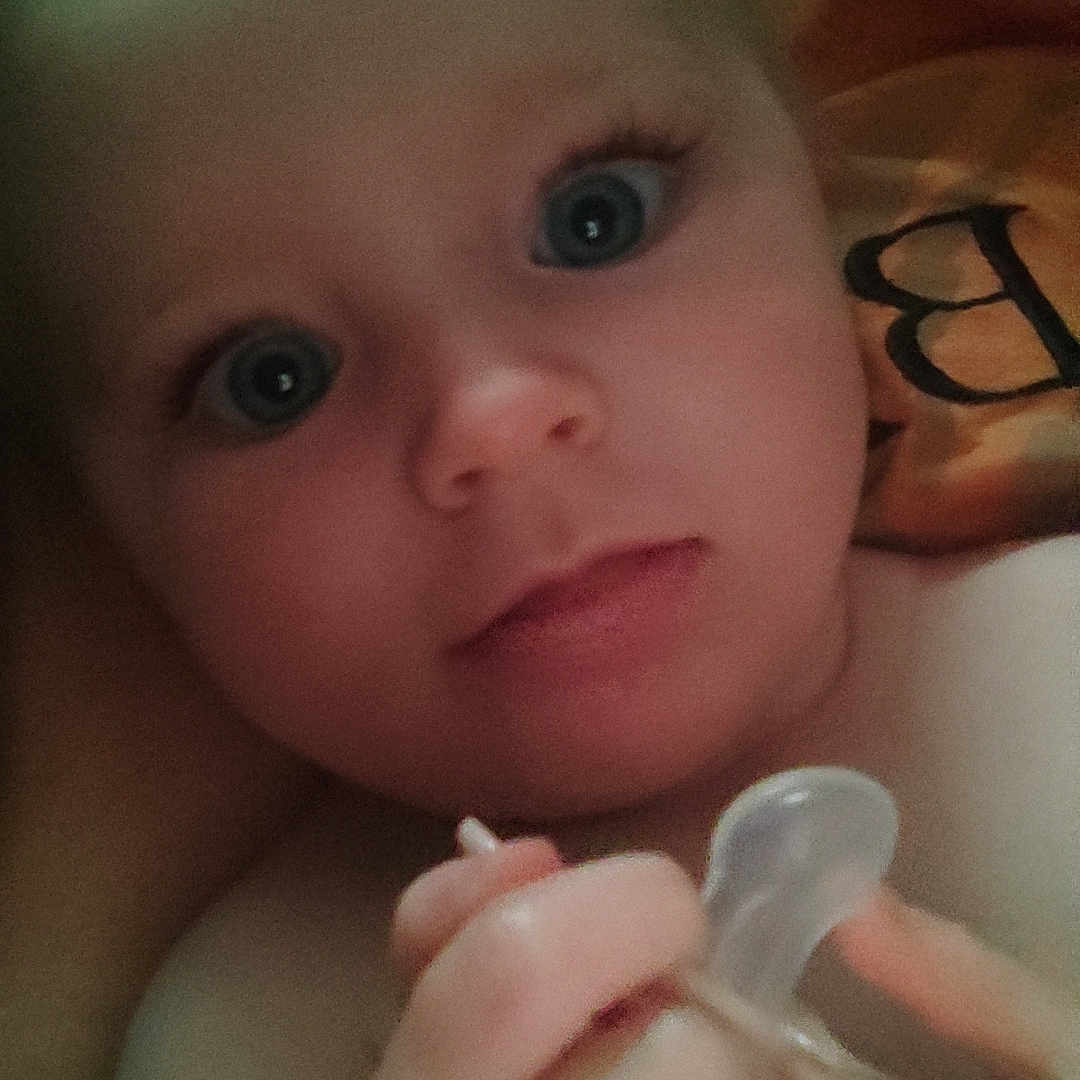 Myanna a rejoint le concours — aidez-le/la à gagner de superbes lots ! baby, blanket, blue_eyes, child, closeup, cute, expression, face, hand, holding, indoors, infant, looking, pacifier, person, portrait, skin, soft_light, warm, young