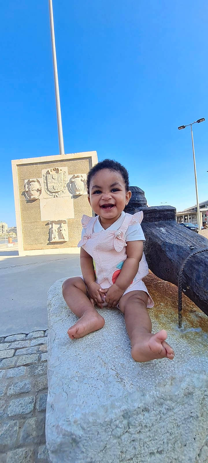 Mouzna participe au concours pour gagner de l'argent avec cette photo : baby_toddler_clothing, barefoot, child, city, concrete, foot, fun, happy, human_leg, joy, leisure, person, sand, sitting, sky, smile, street_light, t_shirt, thigh, toddler