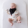 Noah is registered to the contest to win money with this photo: baby, infant, child, smiling, portrait, lying_down, blanket, white_background, bib, onesie, clothing, mittens, cars, vehicle_pattern, bare_feet, indoor, happy, cute, face, photography