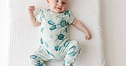 Noah is registered to the contest to win money with this photo: baby, child, infant, smiling, portrait, lying_down, blanket, white_background, onesie, pajamas, turtle_pattern, sea_turtles, clothing, face, hands, feet, indoor, bed, happy, photography