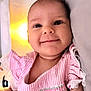 baby, child, closeup, comfortable, cozy, cute, face, happy, indoors, infant, lying_down, pillow, pink_clothing, portrait, small_person, smiling, soft_texture, striped, warm_light, young_child
