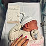 newborn, baby, sleeping, hospital, bassinet, blanket, mittens, hat, hand, nail_art, rings, card, pink, white, cute, peaceful, infant, swaddled, closeup, portrait