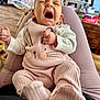 baby, infant, yawning, pink_outfit, bunny_design, legs, indoor, home, cozy, furniture, wooden_floor, blurred_background, person, cute, child, soft_lighting, clothing, sitting, hands, face