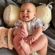 Pippa is registered to the contest to win money with this photo: baby, child, closeup, clothing, couch, cute, fabric, feet, hands, happy, indoors, infant, playful, plush_pillow, portrait, relaxed, skin, smiling, soft_toys, tongue