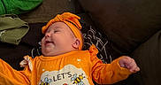 Galaxy Watts joined the competition — help win amazing prizes! baby, bedroom, blue_pants, casual, child, clothing, couch, cozy, cute, fabric, happy, headband, indoor, infant, orange_clothing, person, relaxed, smile, smiling, text_on_clothing