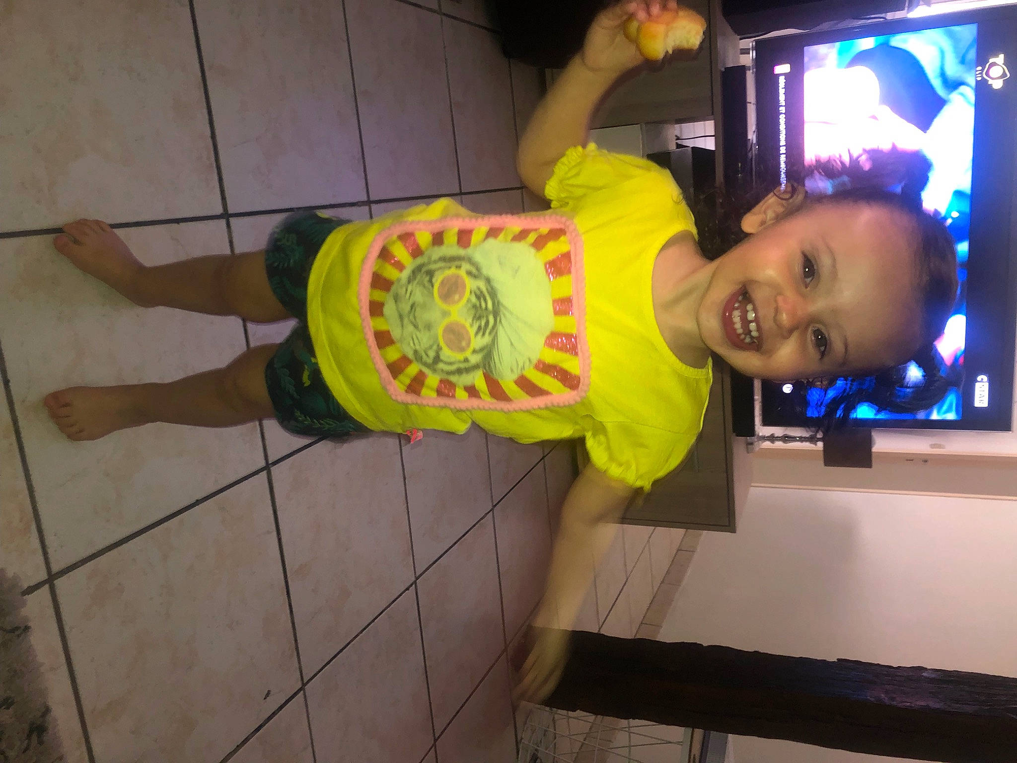 Mia participe au concours pour gagner de l'argent avec cette photo : child, cleanliness, display_device, elbow, flooring, foot, fun, human_leg, joy, knee, led_backlit_lcd_display, person, sandal, smile, thigh, toddler, wrist