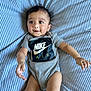 Risha joined the competition — help win amazing prizes! baby, infant, child, onesie, nike_air, striped_bed_sheet, blue_and_white, smiling, happy, curious, lying_down, indoor, cute, young_child, arms_outstretched, clothing, portrait, face, person, skin