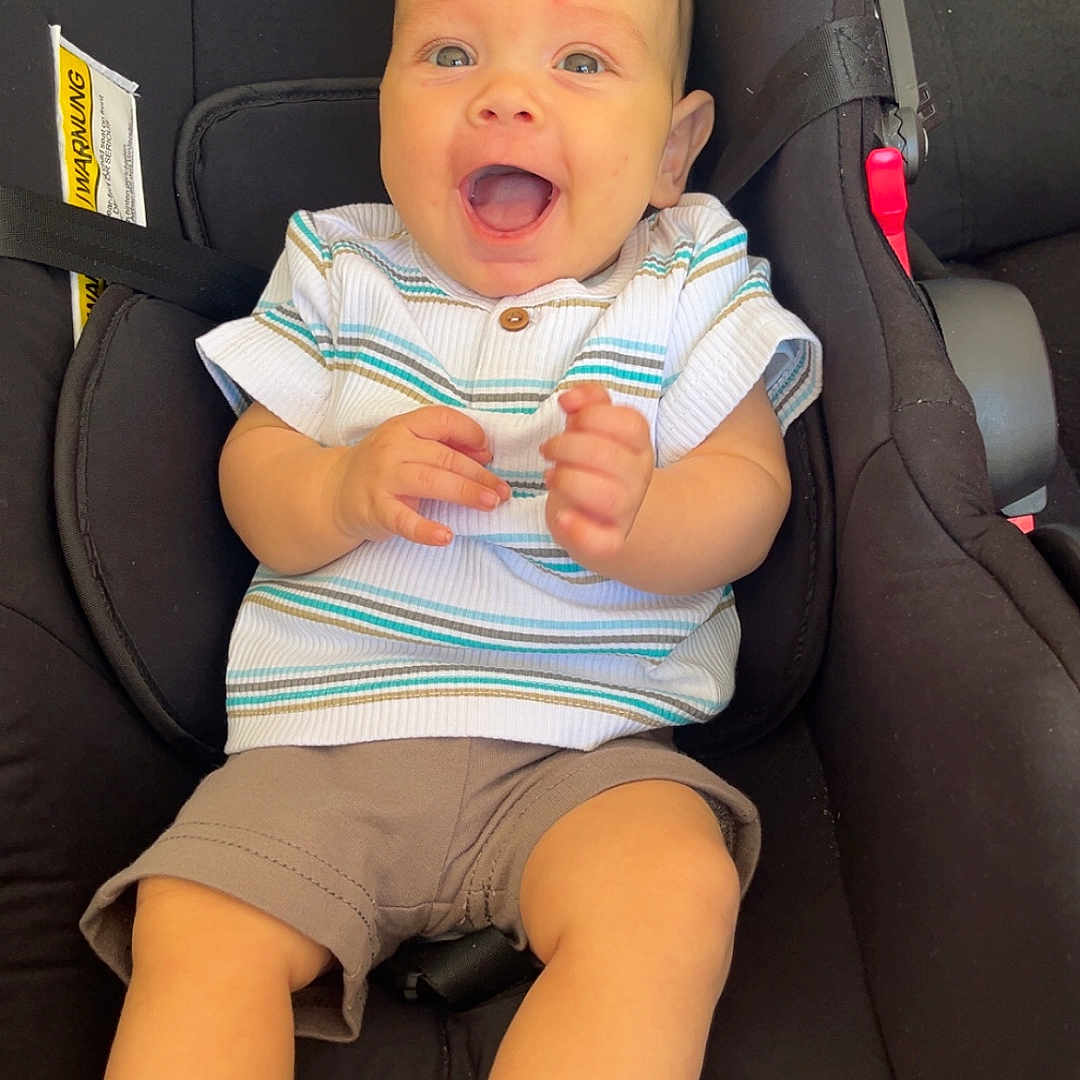 Tiago participe au concours pour gagner de l'argent avec cette photo : baby, barefoot, bright, car_seat, child, clothing, comfort, cute, expression, happy, indoor, infant, person, portrait, seatbelt, shirt, shorts, sitting, smiling, young_child