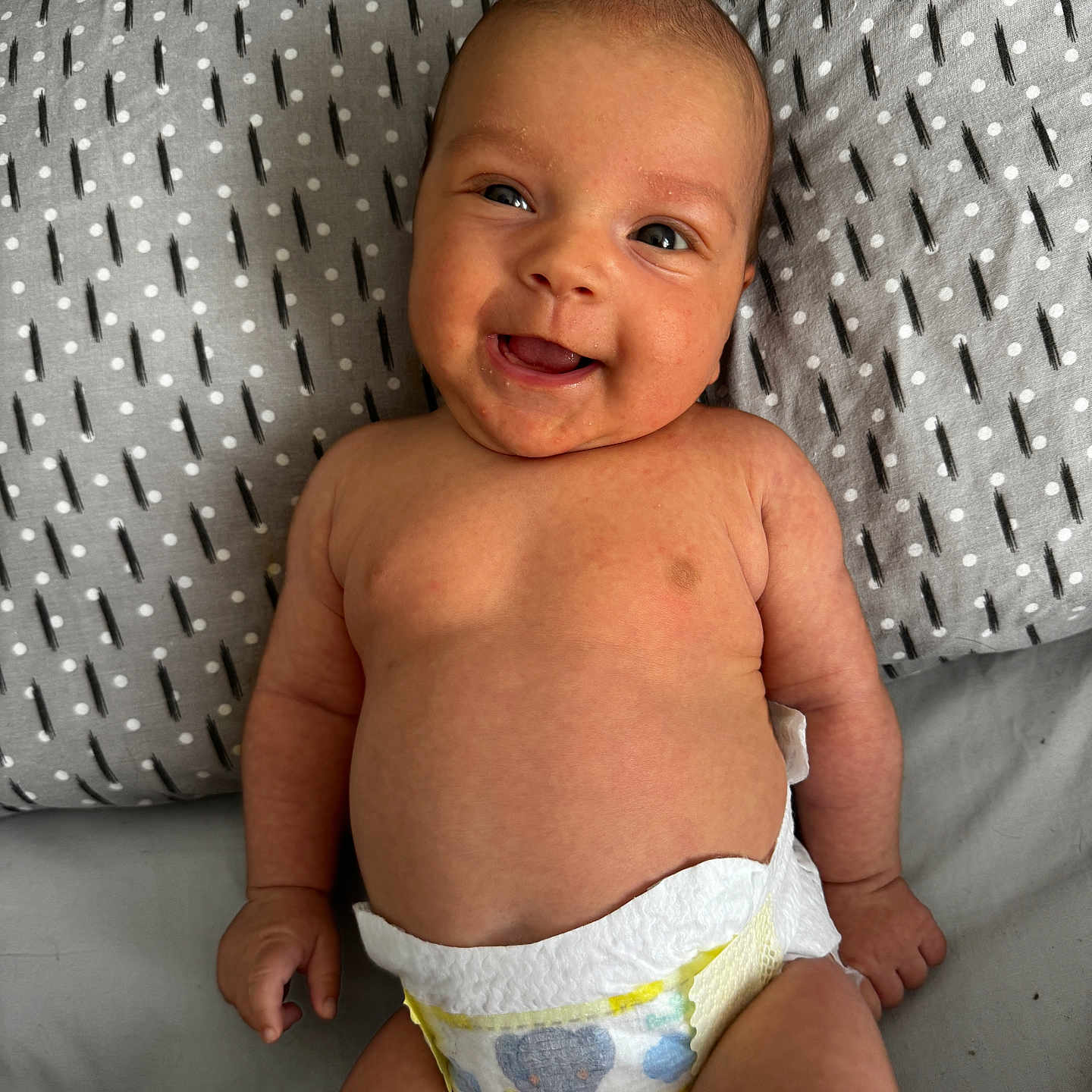 Yaasamin joined the competition — help win amazing prizes! arm, baby, bed, child, chubby, cute, diaper, elephant_print, face, grey_sheet, hand, happy, head, infant, leg, lying_down, patterned_pillow, pillow, skin, smiling