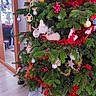 christmas_tree, cat, ornaments, tinsel, holiday, decorations, indoor, festive, greenery, white_cat, fluffy, red_tinsel, silver_baubles, wood_floor, mirror, reflection, star_ornament, bells, reindeer_ornament, holiday_spirit