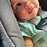 baby, child, face, eyes, car_seat, seatbelt, clothing, green_shirt, frog_print, skin, closeup, infant, cute, portrait, sitting, strapped, safety, expression, adorable, indoors