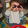 Braxton joined the competition — help win amazing prizes! baby, child, toddler, sunglasses, striped_shirt, walker, toy, sunlight, outdoor, curly_hair, face, hands, play, seat, colorful, person, infant, casual, cute, fun