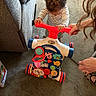 Braxton is registered to the contest to win money with this photo: activity, baby, carpet, child, colorful_toy, couch, curly_hair, floor, footwear, hand, indoor, learning, leopard_print, person, playing, striped_shirt, support, toddler, toy_walker, young_child