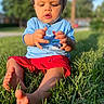 barefoot, blue_shirt, child, curious, daylight, drool, grass, greenery, lawn, nature, outdoor, person, playing, portrait, red_shorts, sitting, summer, sunlight, toddler, young_child
